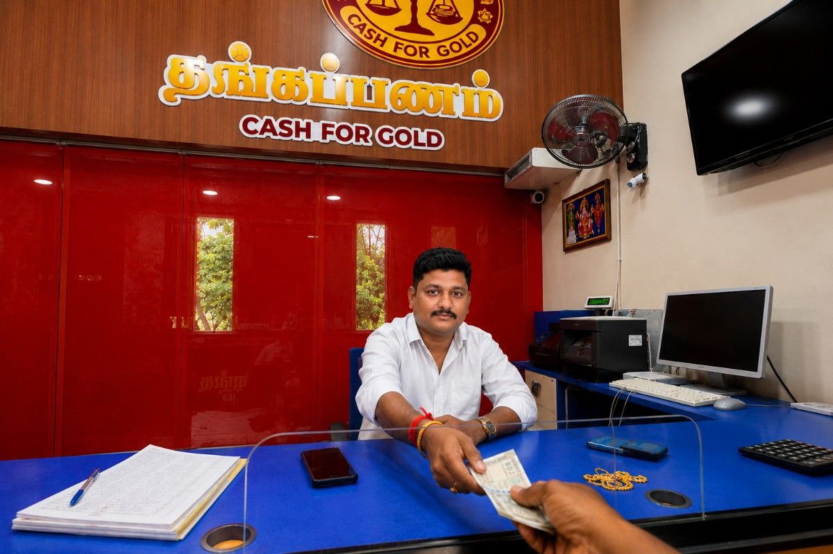 Customer receiving immediate cash payment after successful gold valuation at Thangapanam